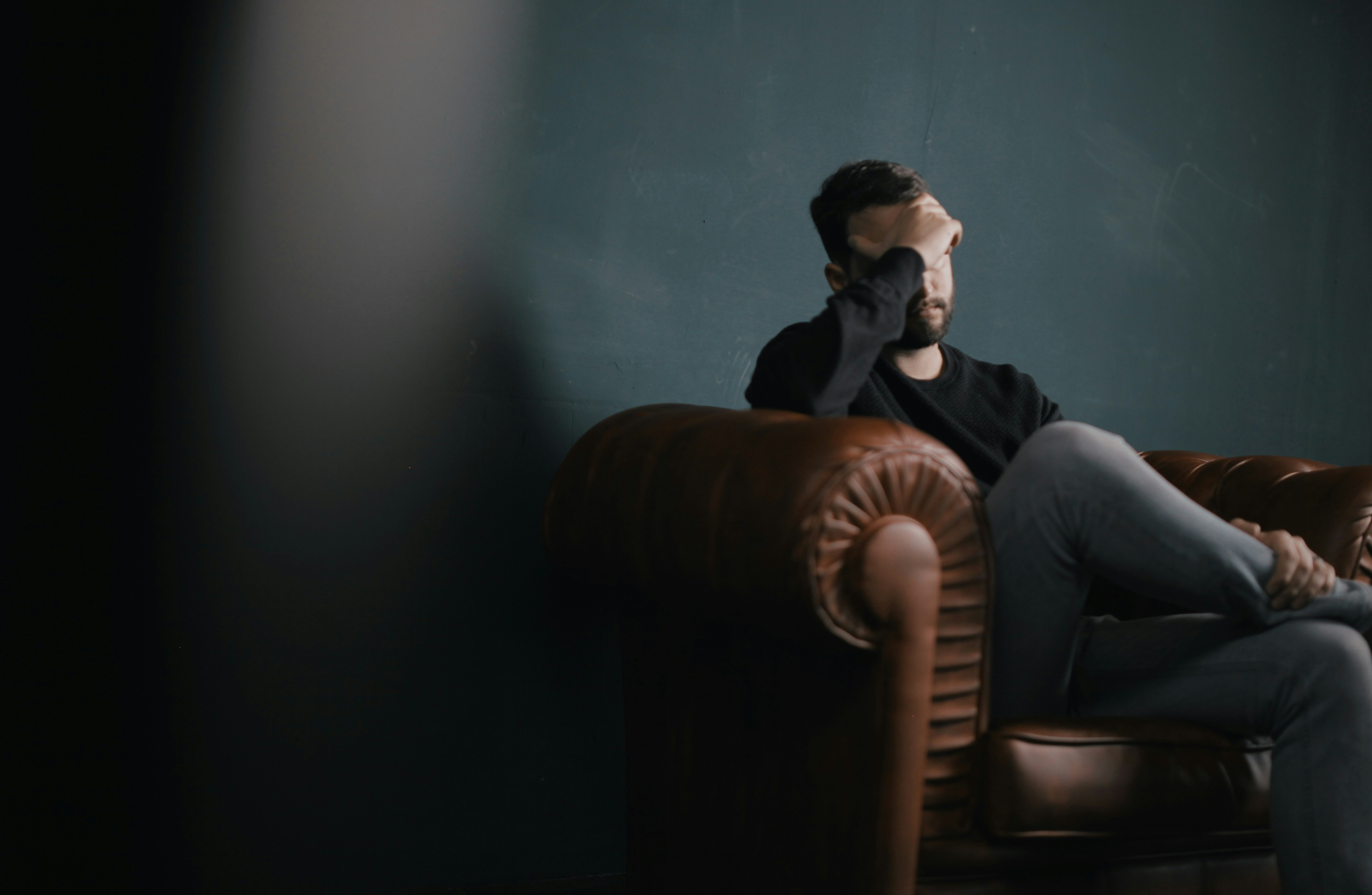 Man sitting with had over face symbolising a struggle with trauma